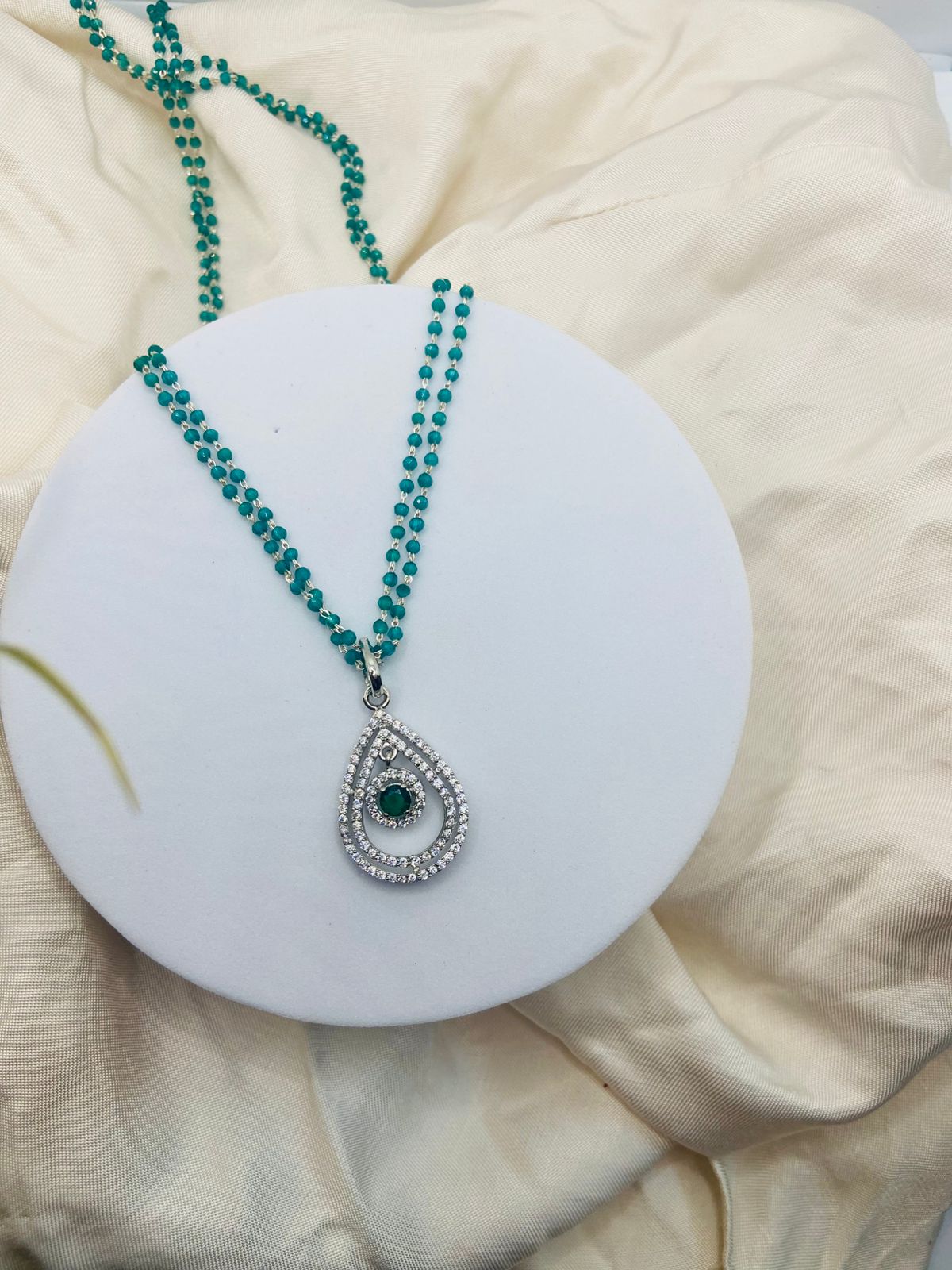 Teardrop Pendant Necklace,paired with a double-strand green pearl chain.